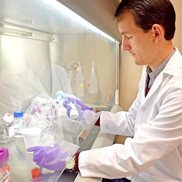 研究人员在实验室外套使用设备来填满一个集装箱液体在屏幕后面。